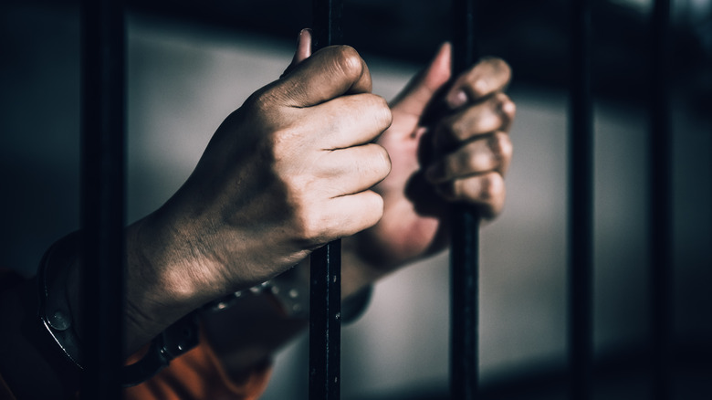 A handcuffed person behind bars