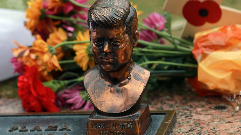 bust of John F. Kennedy at memorial with flowers