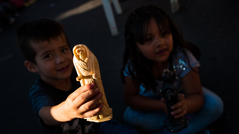 Children playing with Santa Muerte statues