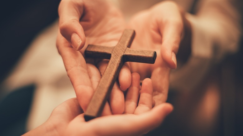 Hands holding a wooden cross