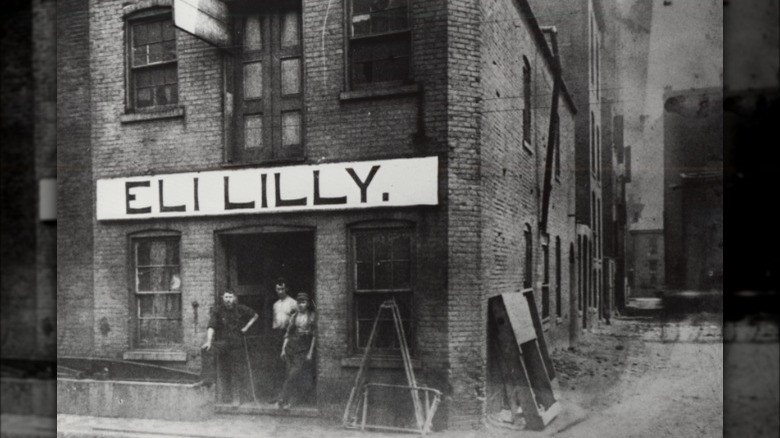 Eli Lilly standing in front of brick building 1800s