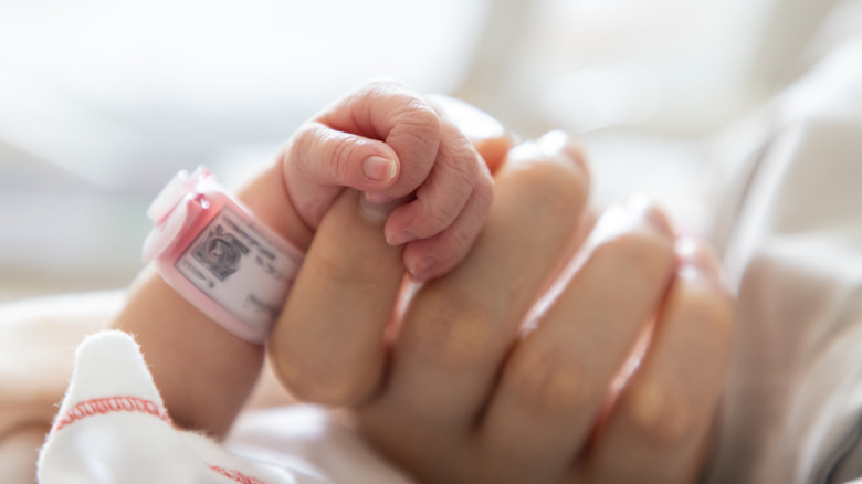 a newborn baby holding its mother's hand
