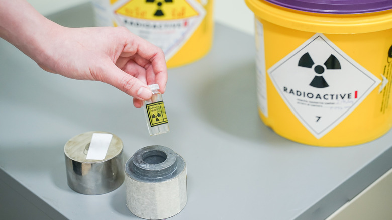 hand holding a vial with a radioactive material label