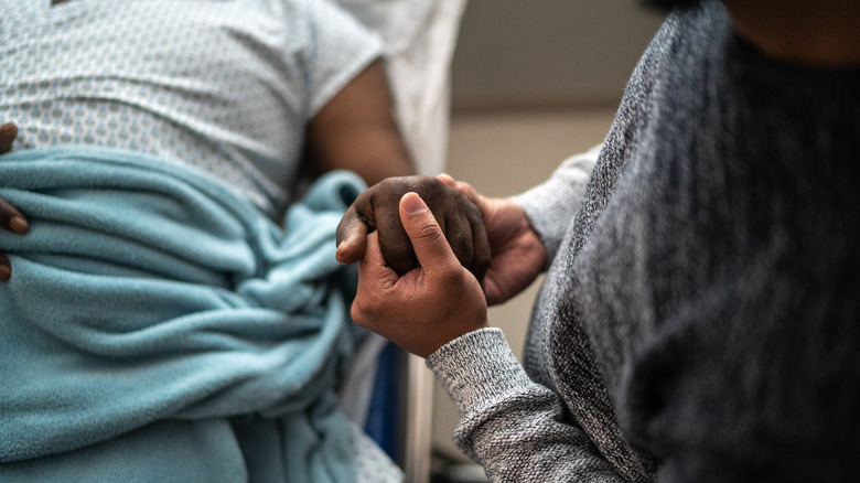 Sick person holding loved one's hand