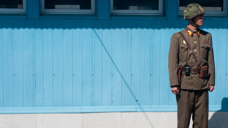 North Korean soldier standing guard blue wall