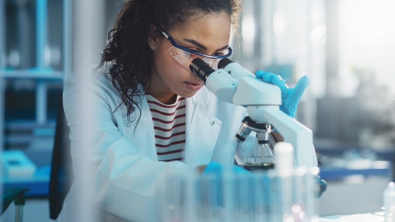 scientist peers through microscope