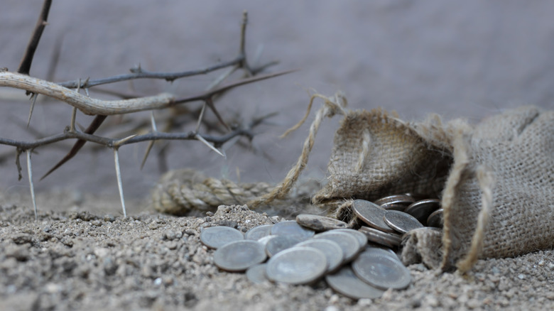 Silver coins next to crown of thorns