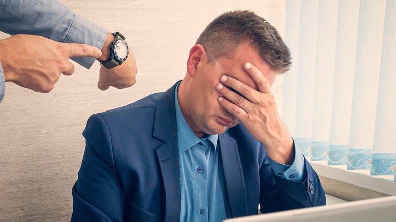 man shows watch to flustered employee