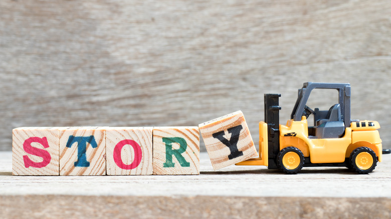 toy blocks spelling "story" with a truck picking up the letter Y