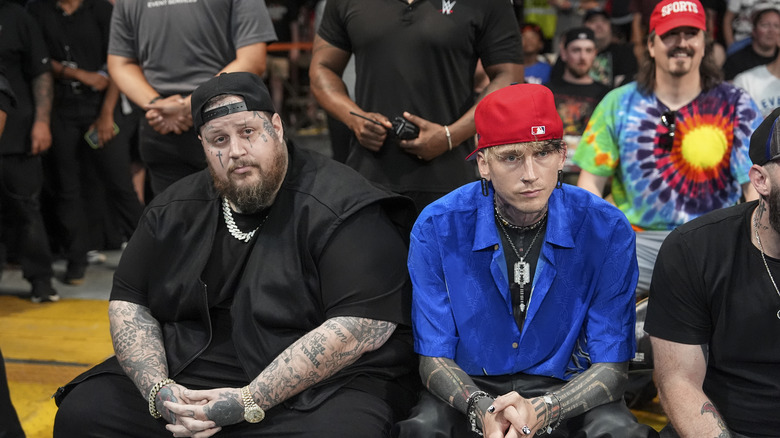 Jelly Roll and Machine Gun Kelly seated in crowd