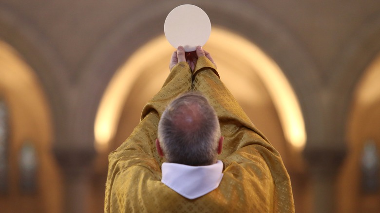 Priest holding up a host