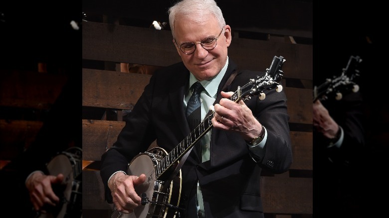 Steve Martin smiles and plays banjo