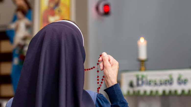 Nun gripping rosary during prayer