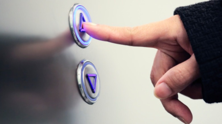 Hand pushing up button on elevator