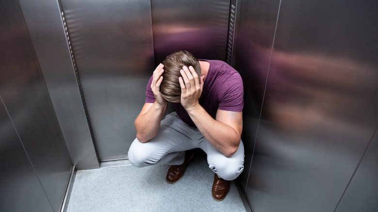 Crouching man trapped in elevator