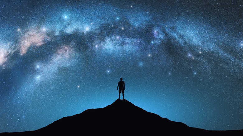 Person standing on mountain under Milky Way