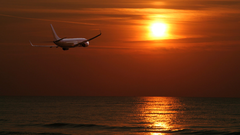 Plane flying West toward sun