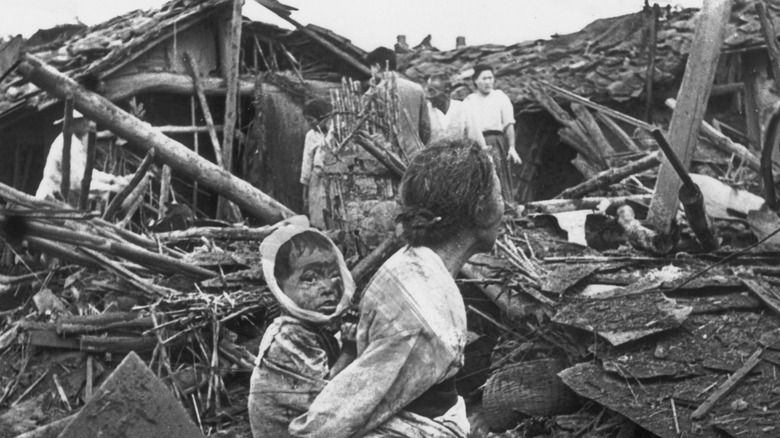 A woman and child standing in a bombed out town