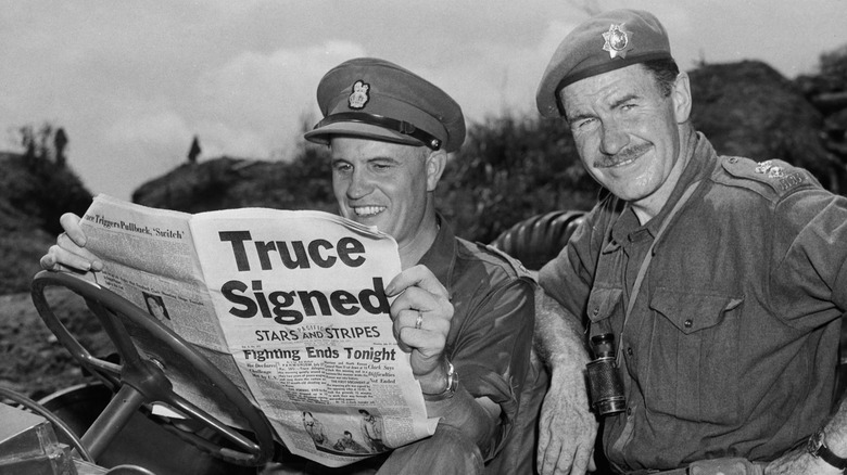 Canadian soldiers holding a newspaper announcing the armistice.