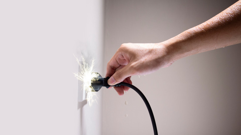 hand plugging cord outlet sparks flying