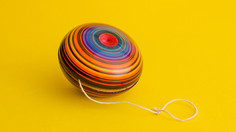 A colorful wooden yo-yo with some of its string extended