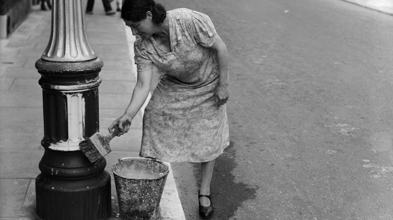 woman painting a lamppost during the blackout