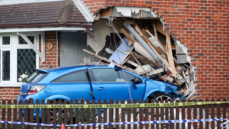 Blue car collides with brick house 